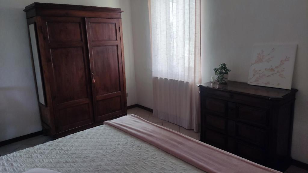een slaapkamer met een bed, een houten kast en een raam bij Agriturismo Le grondaie in Siena