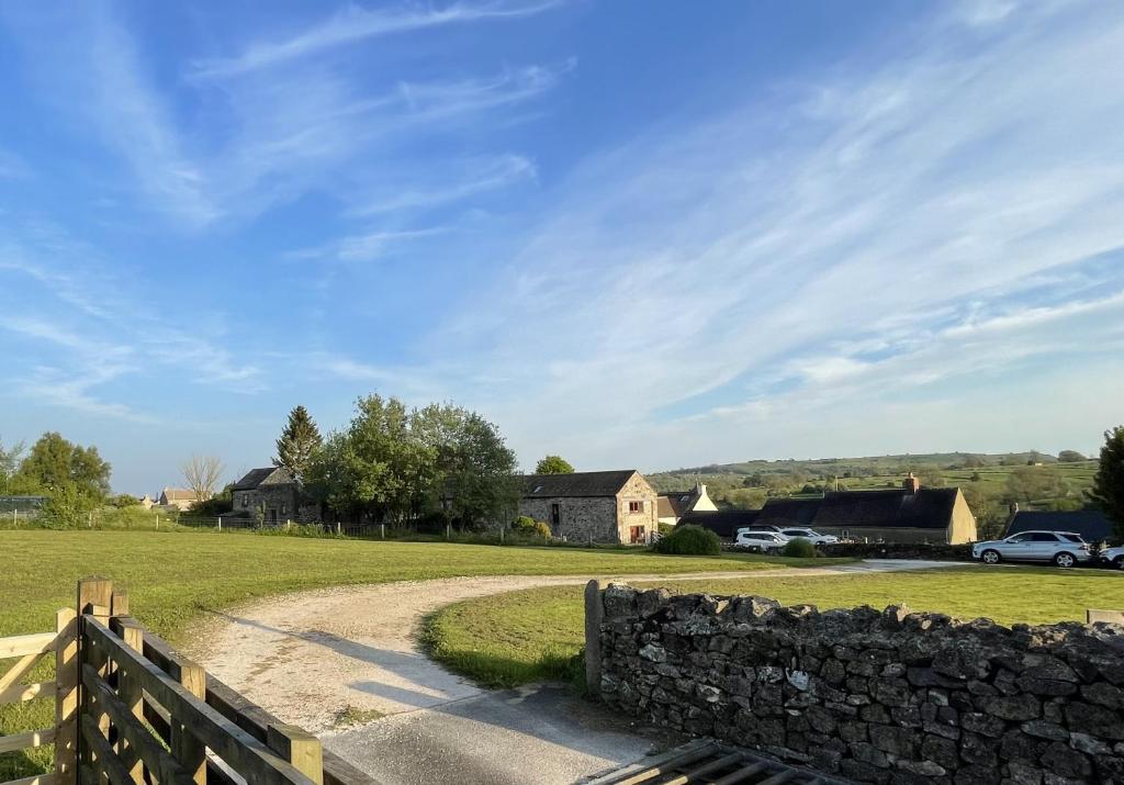 a road in a field with a stone fence at Chestnut Farm Holiday Cottages in Matlock