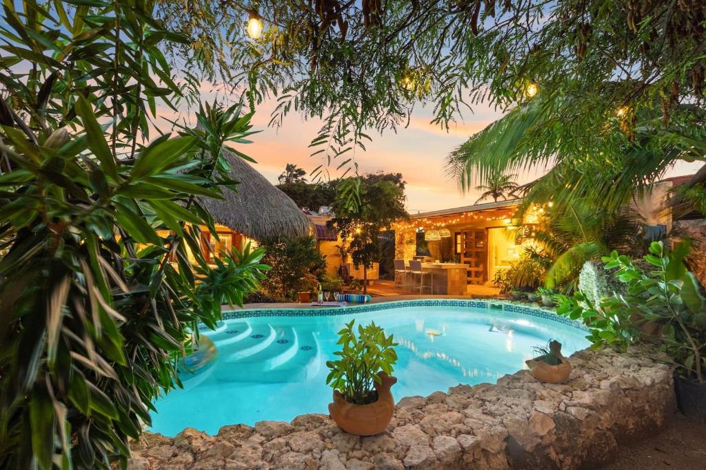 Savaneta的住宿－Villa Laurence Aruban Oasis Footsteps To Ocean，一座树木繁茂的房屋前的游泳池