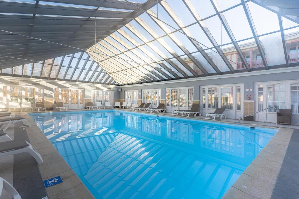 une grande piscine avec un plafond de verre dans l'établissement Beautiful flat with swimming pool tennis court and private car parking 264, à Le Touquet-Paris-Plage