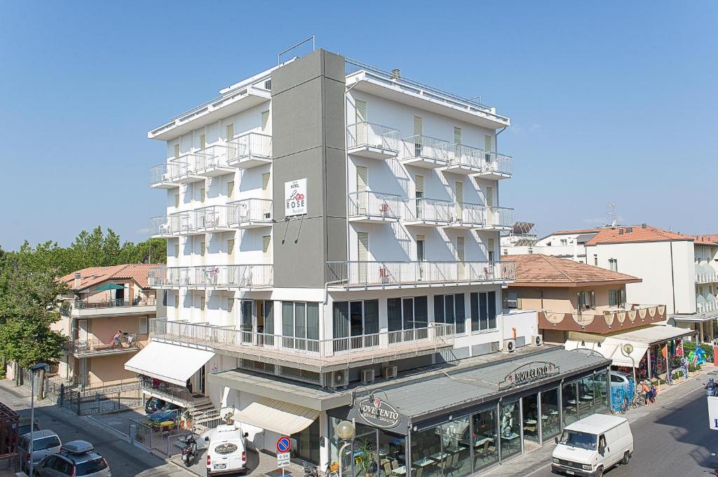 wysoki budynek z samochodami zaparkowanymi przed nim w obiekcie Hotel ROSE NUOVE w Rimini