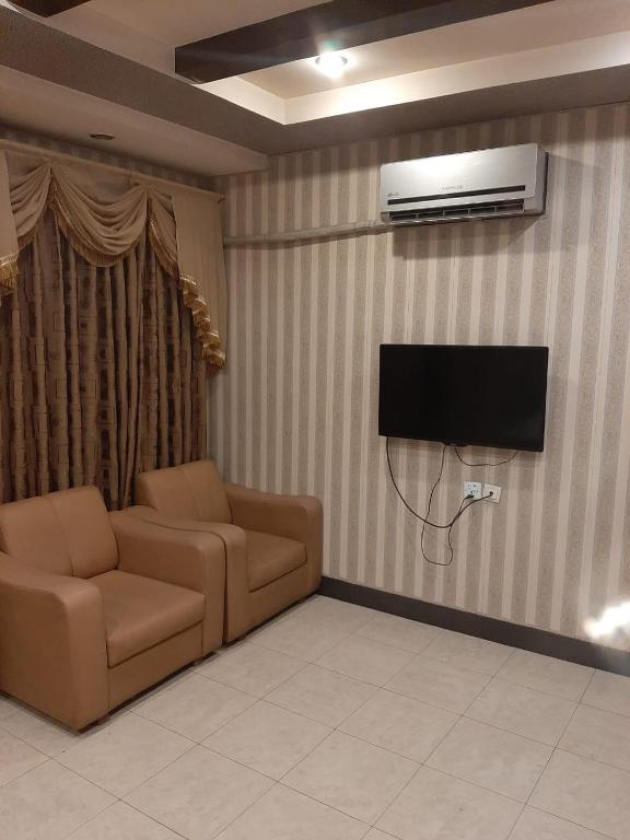 sala de estar con sofá y TV de pantalla plana en Madina Hotel, en Faisalabad