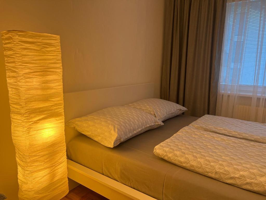 a bedroom with a bed and a lamp next to a window at Aura's Serenity Apartment in Vienna
