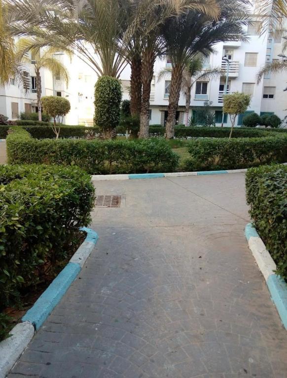 een parkeerplaats voor een gebouw met palmbomen bij Fal Souss 2 T3 in Agadir