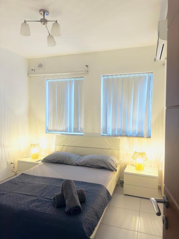 a bedroom with a bed and two windows at Cozy Central Apartment - Swieqi in Is-Swieqi