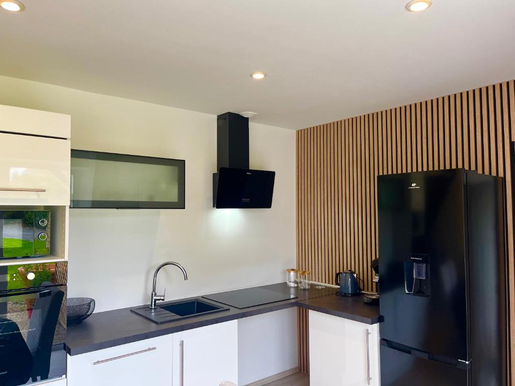 a kitchen with a black refrigerator and white cabinets at Villa du Manoir 1685 in Saint Malo