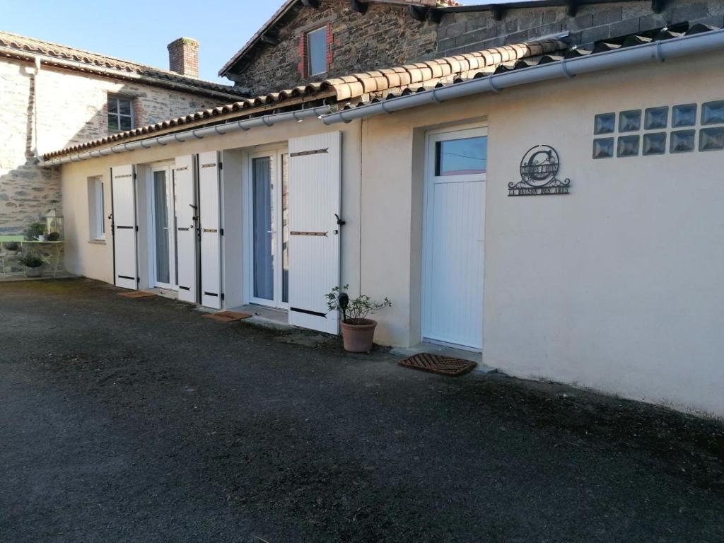 eine Reihe von Gebäuden mit weißen Türen und einer Einfahrt in der Unterkunft La Maison des Amis in Les Essarts