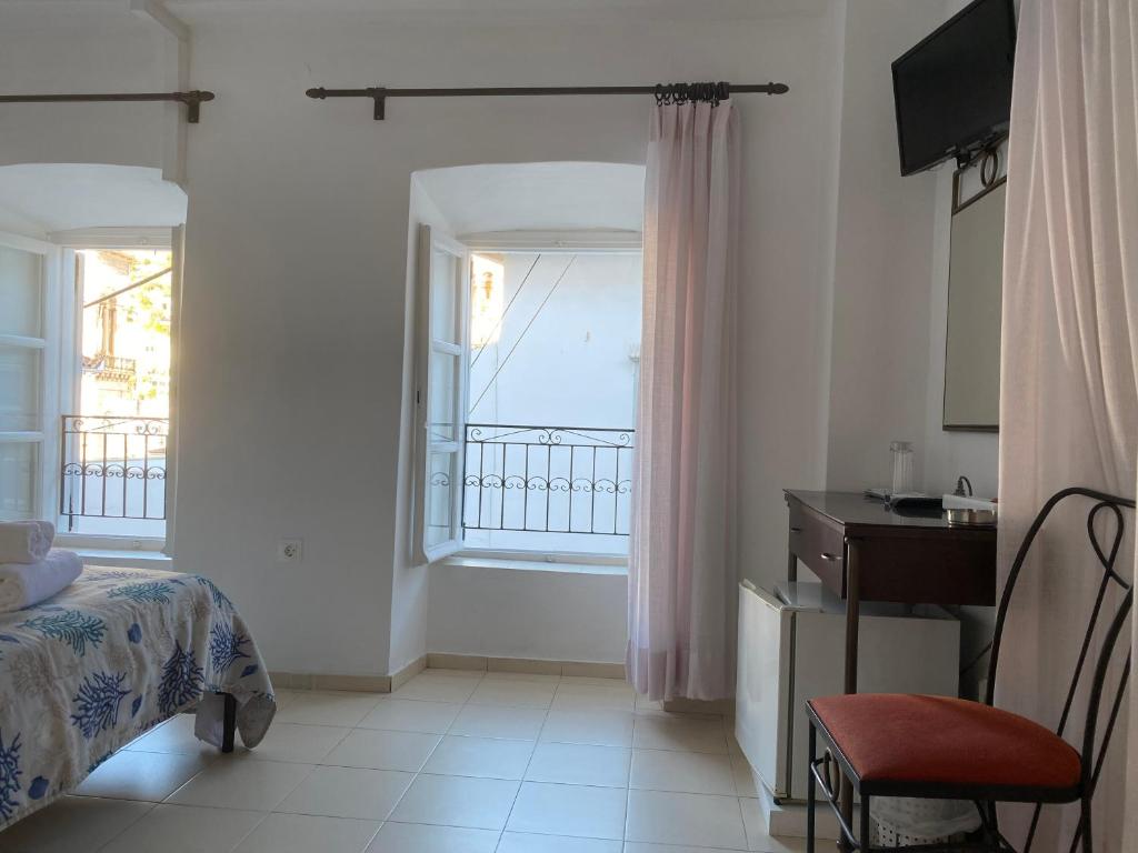 a bedroom with a bed and a desk and a window at Pension Efie in Hydra