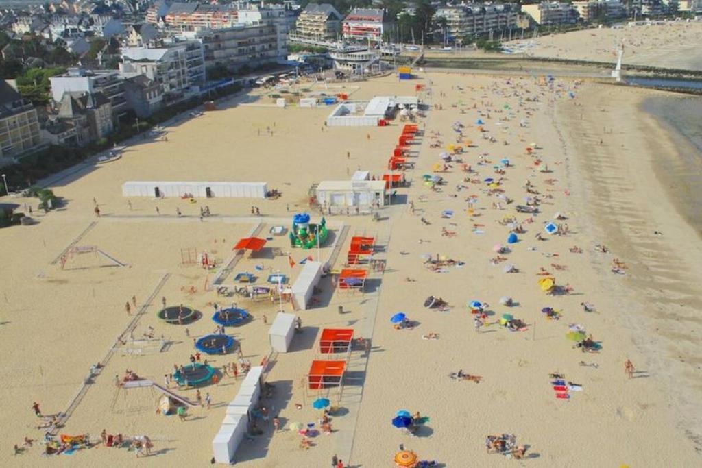 eine Aussicht über einen überfüllten Strand mit Menschen und Sonnenschirmen in der Unterkunft Charmant triplex familial au coeur du Pouliguen, proche de la plage et de la Baule in Le Pouliguen