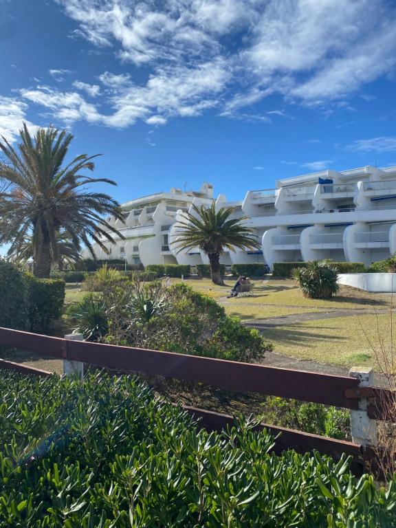 un edificio bianco con palme di fronte di Studio première ligne mer parking a La Grande-Motte
