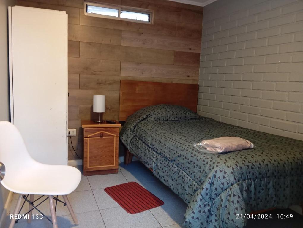 ein Schlafzimmer mit einem Bett und einem weißen Stuhl in der Unterkunft Alojamientos JV HABITACIONES in Nogales