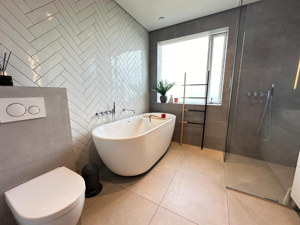 een badkamer met een bad, een toilet en een douche bij House in Hraunbraut in Kópavogur - Birta Rentals in Reykjavík