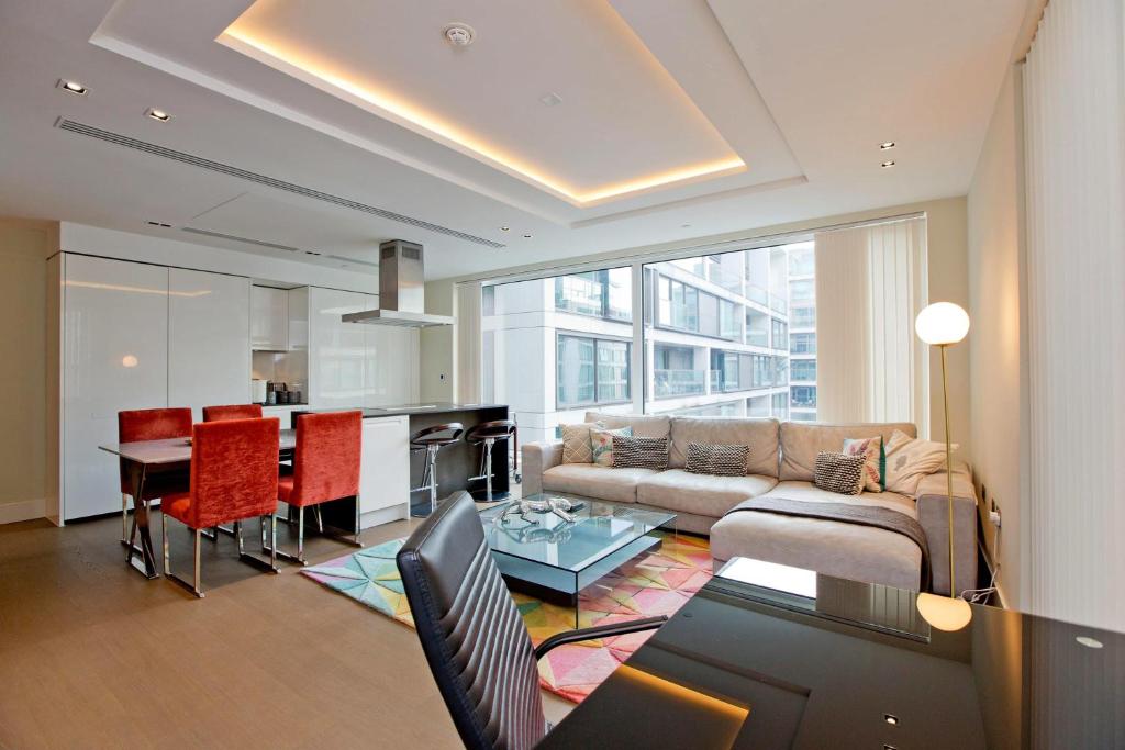 ein Wohnzimmer mit einem Sofa und einem Tisch in der Unterkunft Luxurious West Kensington Flat with City Views in London