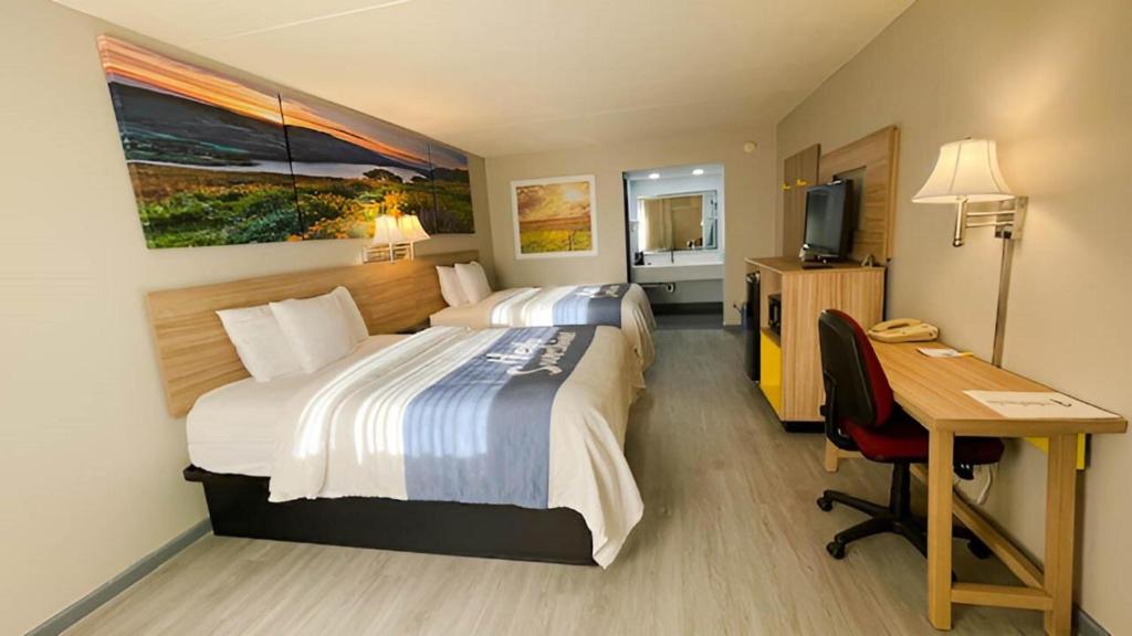 a hotel room with two beds and a desk at Days Inn by Wyndham Salina South in Salina