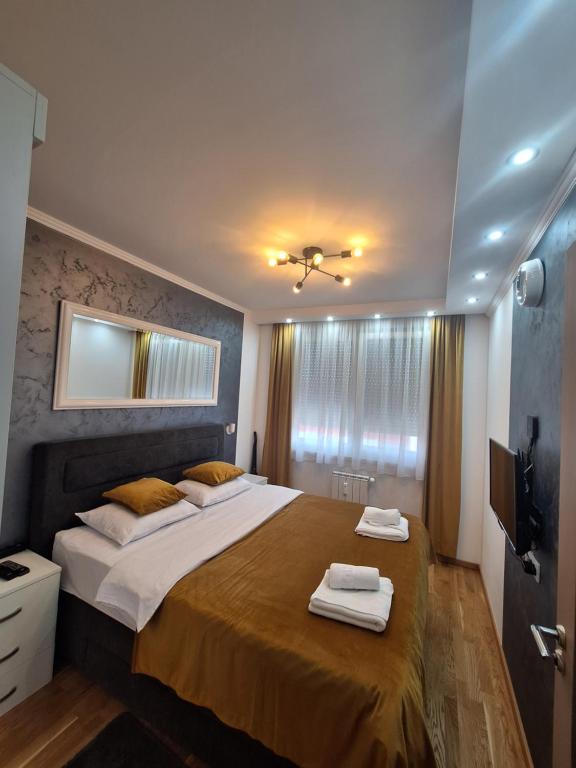 - une chambre avec un grand lit et des serviettes dans l'établissement LUX APARTMENT SANJA 3, à Subotica