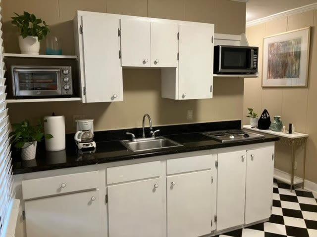 uma cozinha com armários brancos, um lavatório e micro-ondas em Cozy Solo Escape em Lafayette