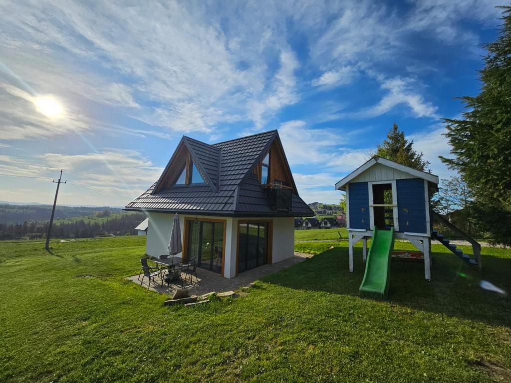 una piccola casa con parco giochi in un campo di Domek Pod Laskiem a Czerwienne