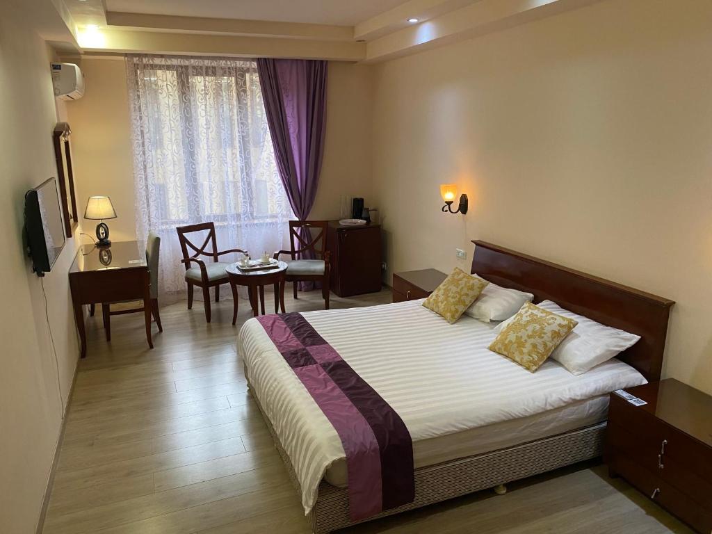 a hotel room with a bed and a table and chairs at DaMus apartments in Yerevan