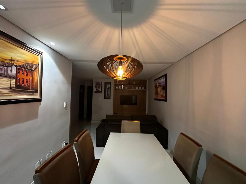 a dining room with a table and chairs and a lamp at Apartamento em área nobre in Conselheiro Lafaiete