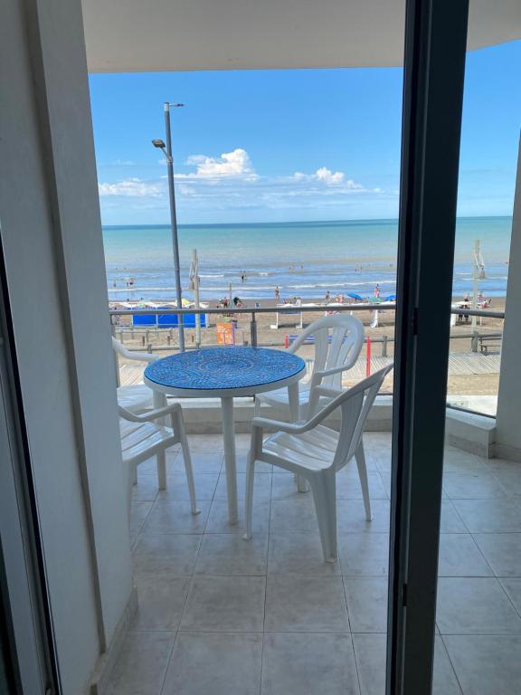 a table and chairs on a balcony with a view of the beach at Departamento frente al mar 1 B in Monte Hermoso