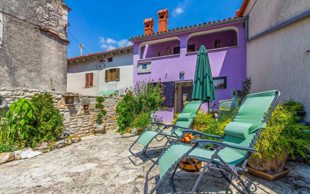 un grupo de sillas y una sombrilla frente a una casa púrpura en Ferienhaus für 5 Personen ca 70 qm in Rakalj, Istrien Bucht von Raša, en Rakalj