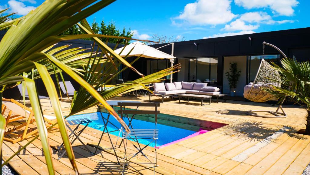 a house with a pool and a patio with a couch at Evasion tropicale in Bretteville-sur-Odon