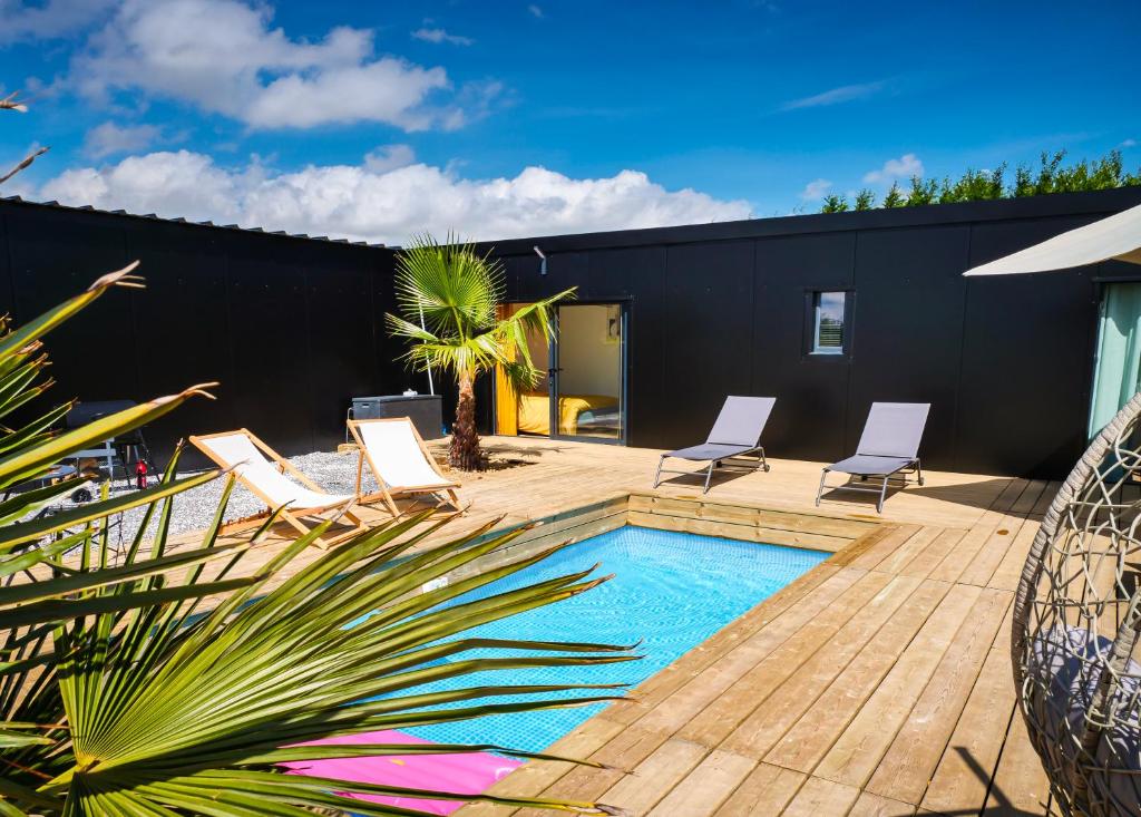 une arrière-cour avec une piscine et des chaises ainsi qu'un bâtiment dans l'établissement Evasion tropicale, à Bretteville-sur-Odon