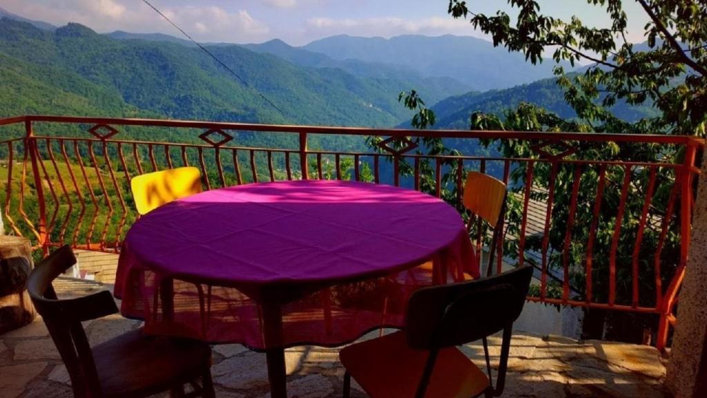 una mesa púrpura en un balcón con vistas a las montañas en Ferienhaus in Caregli mit Garten und Grill, en Borzonasca