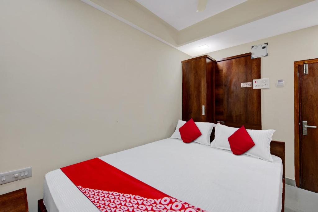 um quarto com uma cama branca e almofadas vermelhas em Super OYO Flagship Hotel Millennia em Visakhapatnam