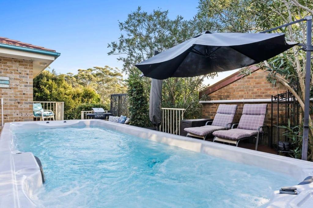 a swimming pool with an umbrella and two chairs and an umbrella at Swim Spa- 5mins to beach and golf - Pet Friendly in Shelly Beach