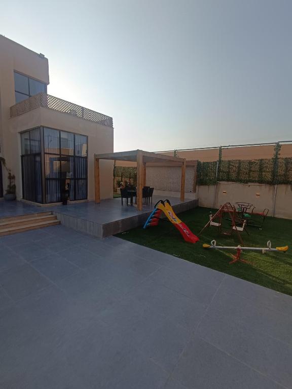 ein Gebäude mit einem Hof mit Spielplatz in der Unterkunft Villa rotana airport road in Al Qasţal