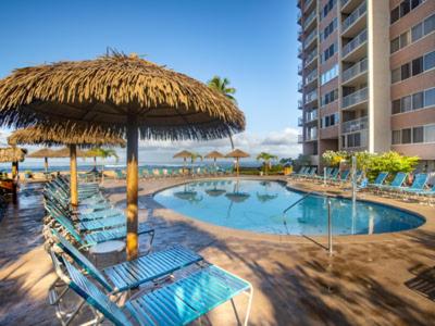 una piscina con sillas y una sombrilla de paja en Royal Kahana Maui by OUTRIGGER en Lahaina