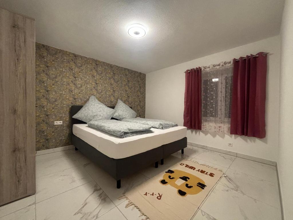 a bedroom with a bed with red curtains and a rug at Safran Apartments Gunzburg in Günzburg