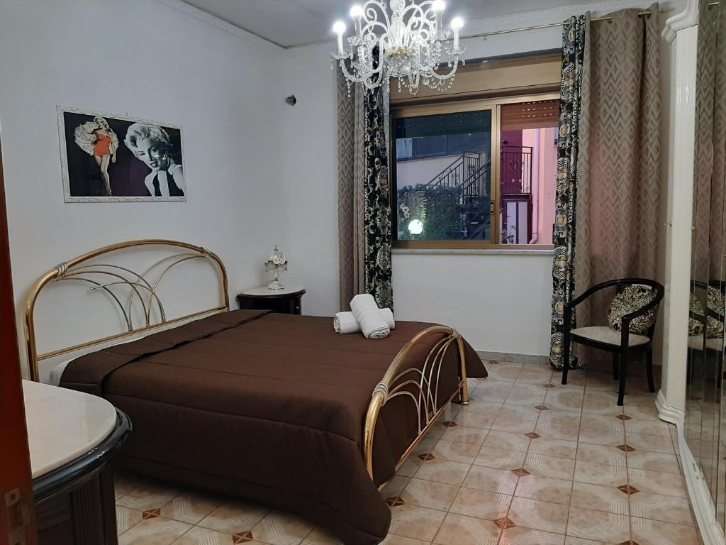 sypialnia z dużym łóżkiem i żyrandolem w obiekcie rossy guest house w mieście Isola delle Femmine