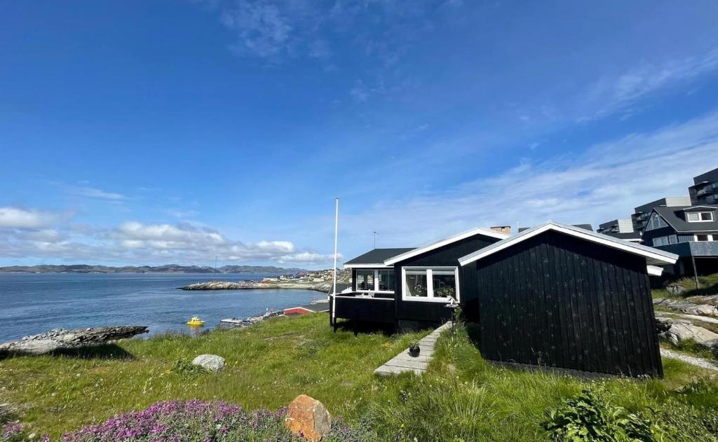 una casa negra en la orilla de un cuerpo de agua en The Black House Tuapannguit 48 en Nuuk