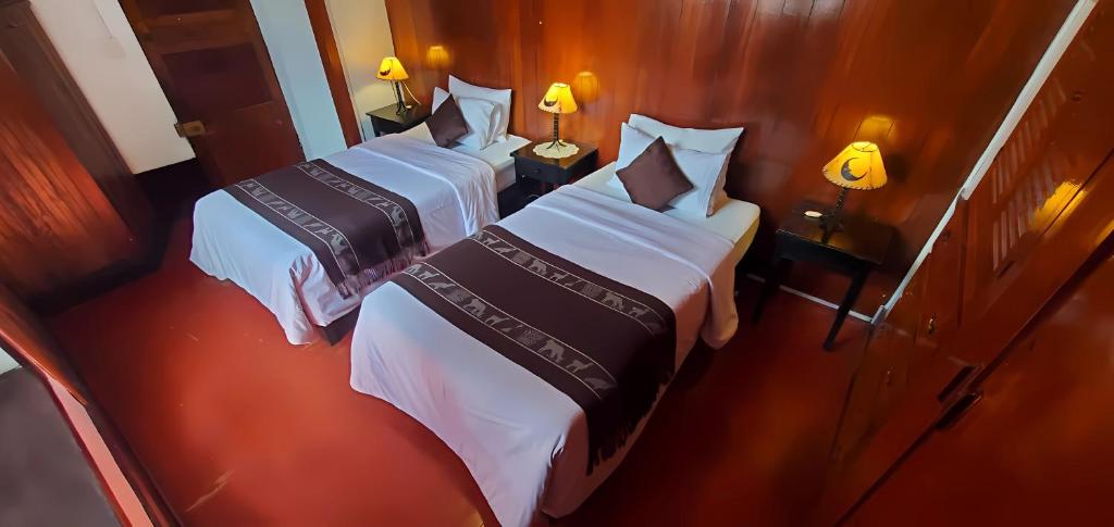 two beds in a hotel room with two lamps at Hotel Campanario in Cusco