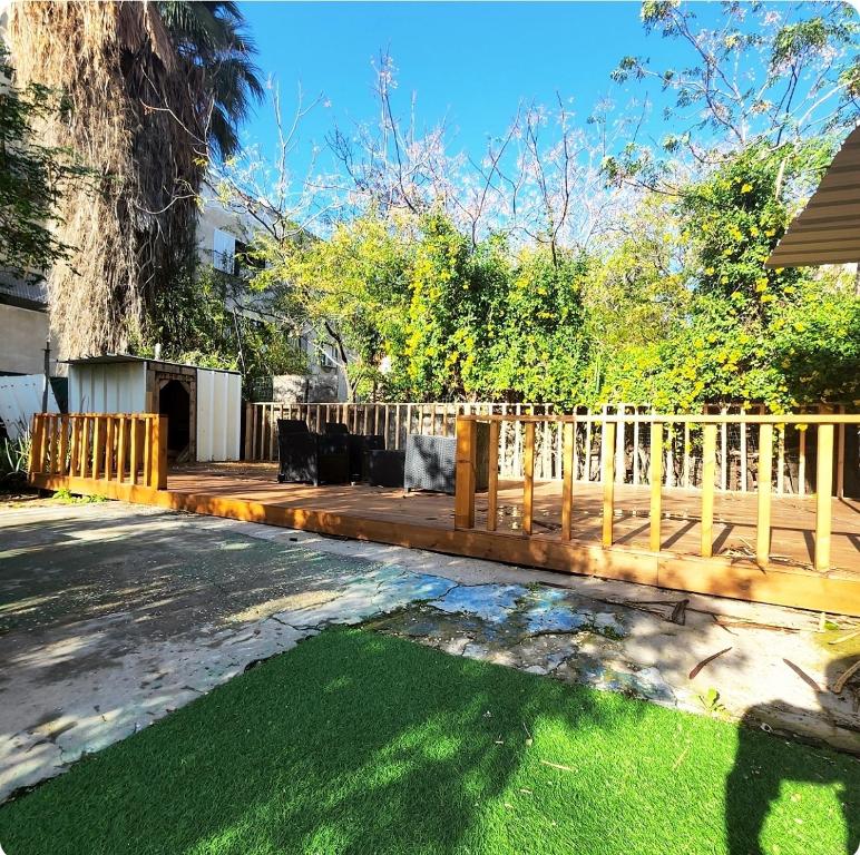 a wooden fence next to a yard with green grass at בית מקסים בלב העיר in Tel Aviv