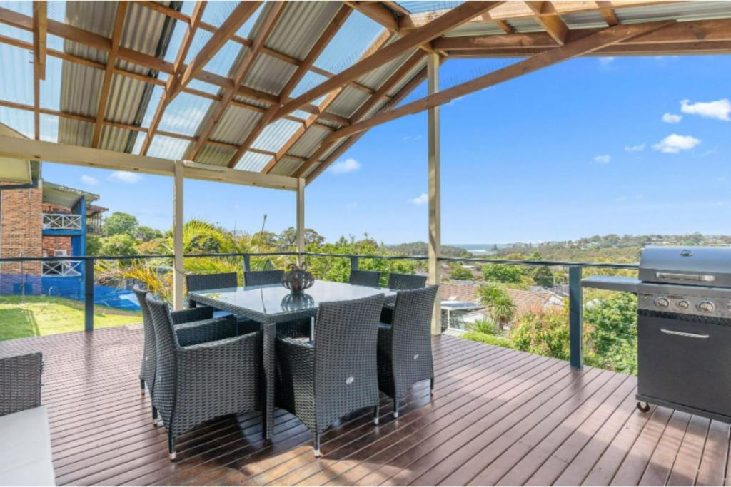 un patio con mesa y sillas en una terraza en Holiday Home with Ocean Views Wamberal, en Wamberal
