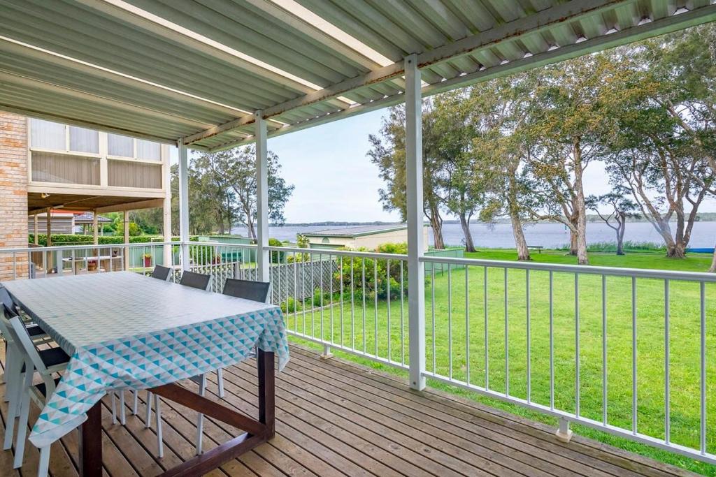 a patio with a table and chairs on a deck at Lake Front Home - Relax & Unwind in Budgewoi