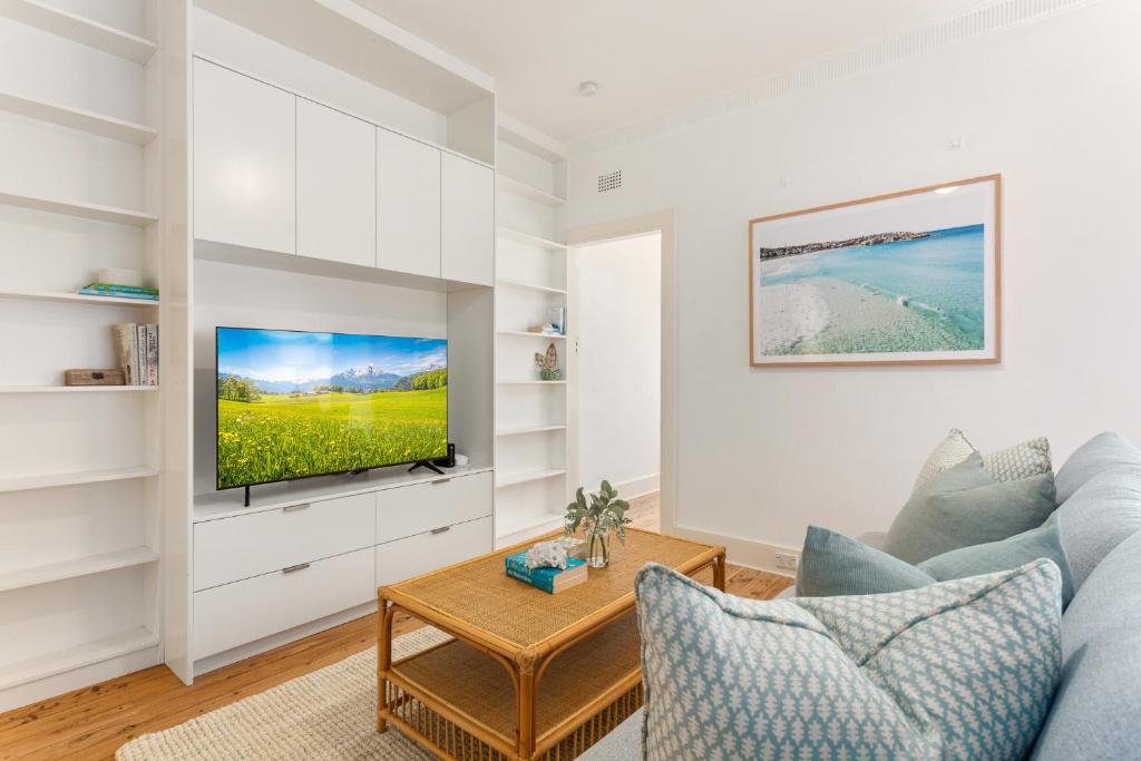 a living room with a couch and a tv at Beachside Living in Modern 2 bedroom Apartment in Sydney