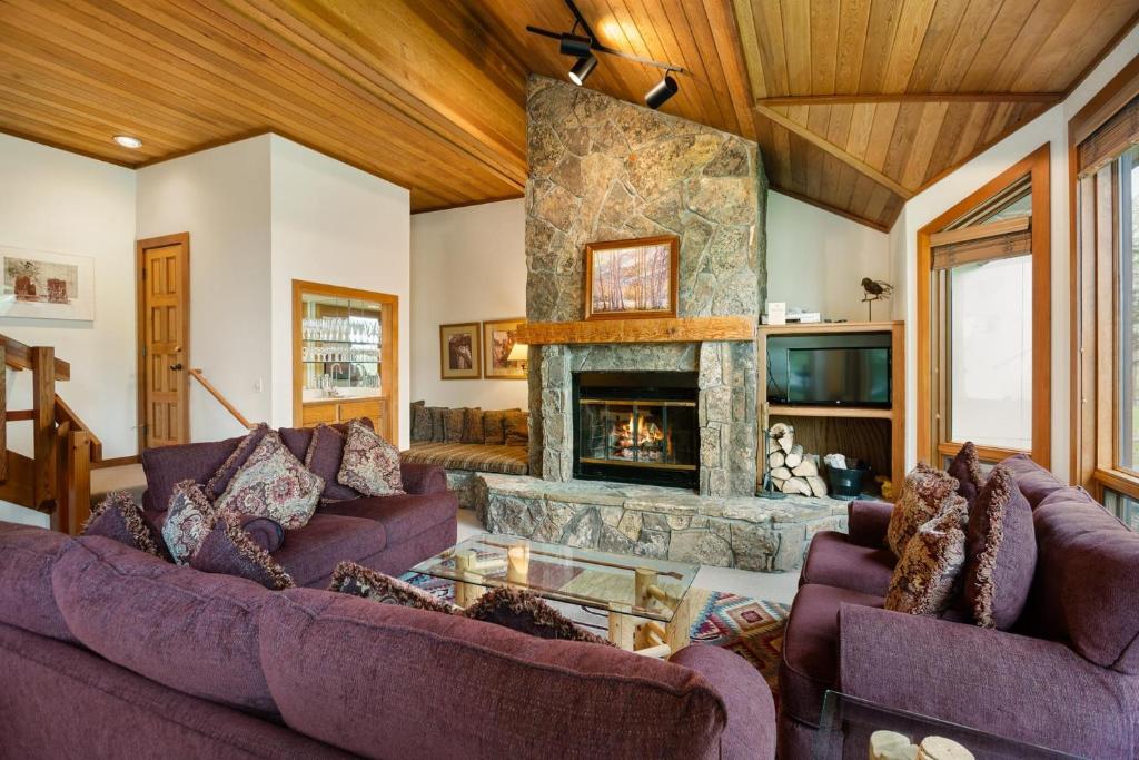 una sala de estar con sofás morados y una chimenea de piedra. en Lovely Townhome with Snowmass View and Ski-In Ski-Out townhouse, en Snowmass Village