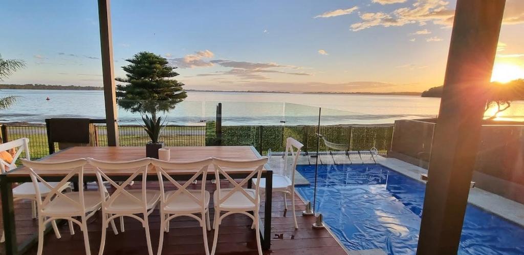 una mesa y sillas en un balcón con piscina en Waterfront Luxury Living & Private Pool Buff Point en Budgewoi
