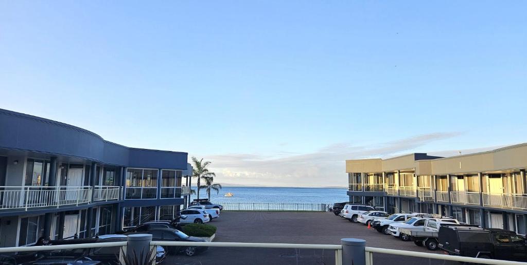 a row of buildings with cars parked next to the ocean at Hilton Motel in Port Lincoln
