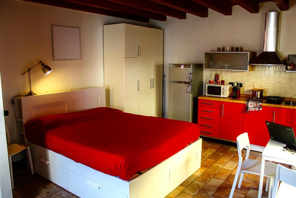a bedroom with a red bed and a kitchen at Bergamo Easy Airport private parking in Bergamo
