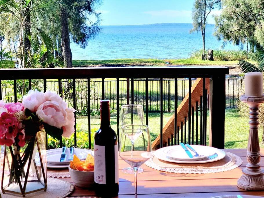 een tafel met een fles wijn en een glas bij Ultimate Lakefront Luxury, Pool Table, Games Room in Berkeley Vale