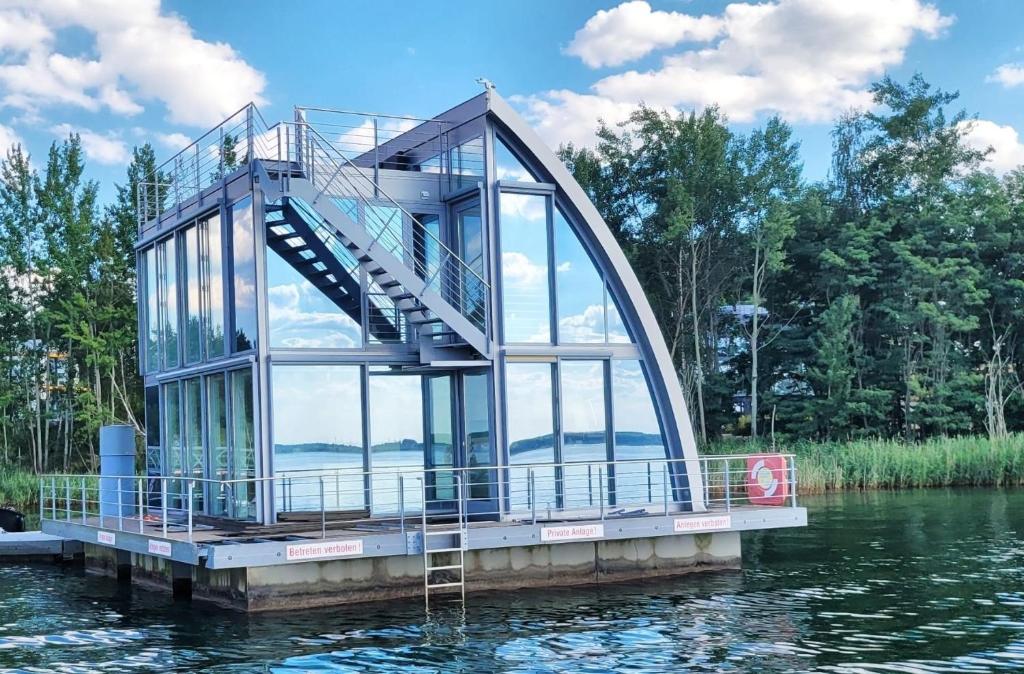 a glass house on a dock in the water at Ferienhaus Water Grundbelegung 4 Pers in Geierswalde