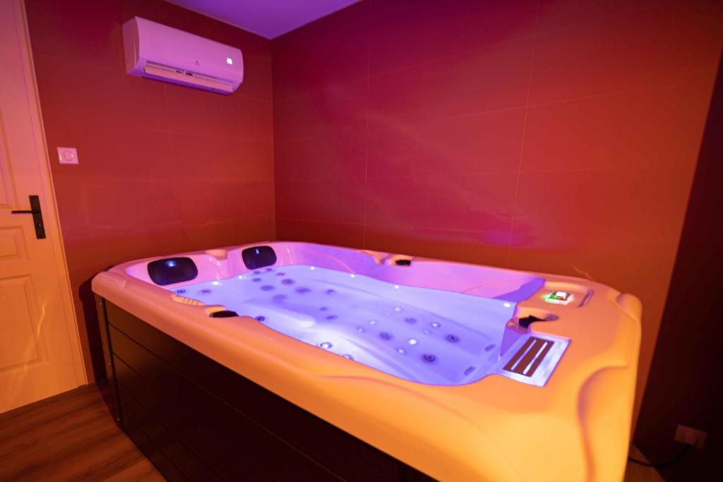 eine Whirlpool-Badewanne in einem Zimmer mit lila Decke in der Unterkunft Suite & SPA privatif Domaine des Demoiselles in Hauteville