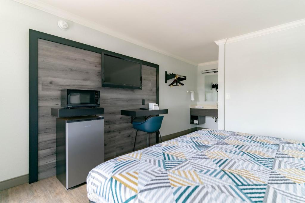 1 dormitorio con 1 cama, escritorio y TV en Motel 6 Pico Rivera - Los Angeles, CA, en Pico Rivera