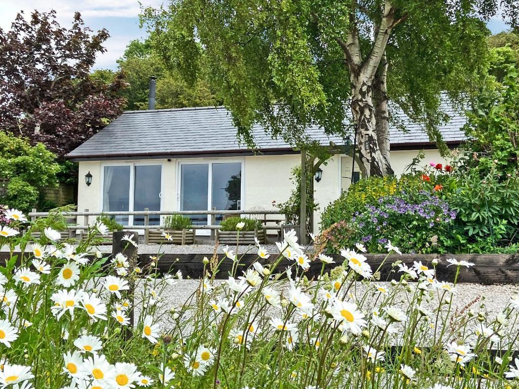 een huis met een bank in een tuin met bloemen bij Beehive Cottage in Bodfari