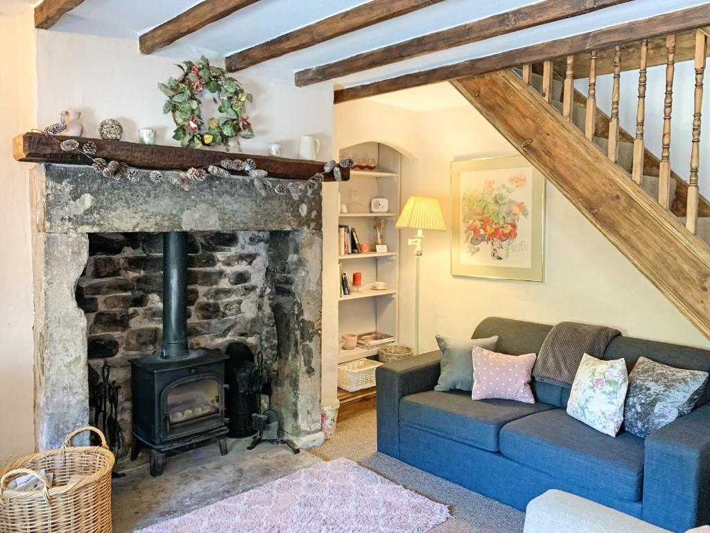 a living room with a fireplace and a blue couch at Golf Cottage in Chinley